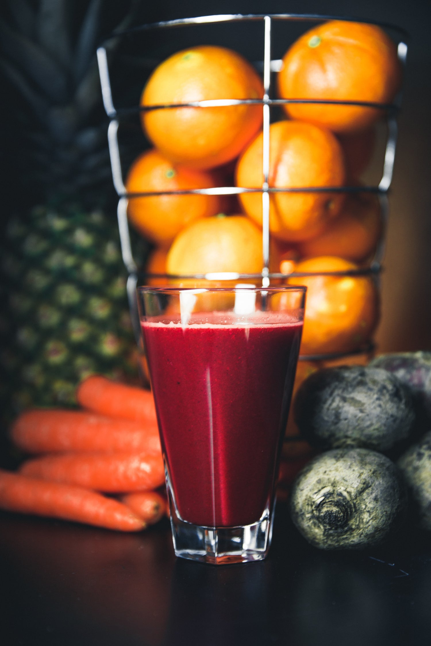 Photo of beet juice in a glass with the rest of the ingredients in the background.